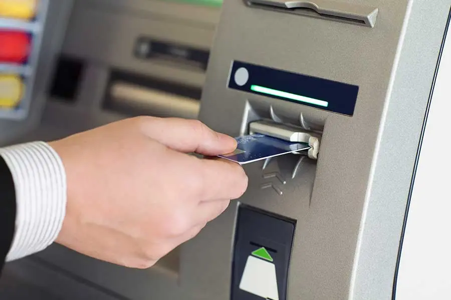 A person is putting money in an atm machine.