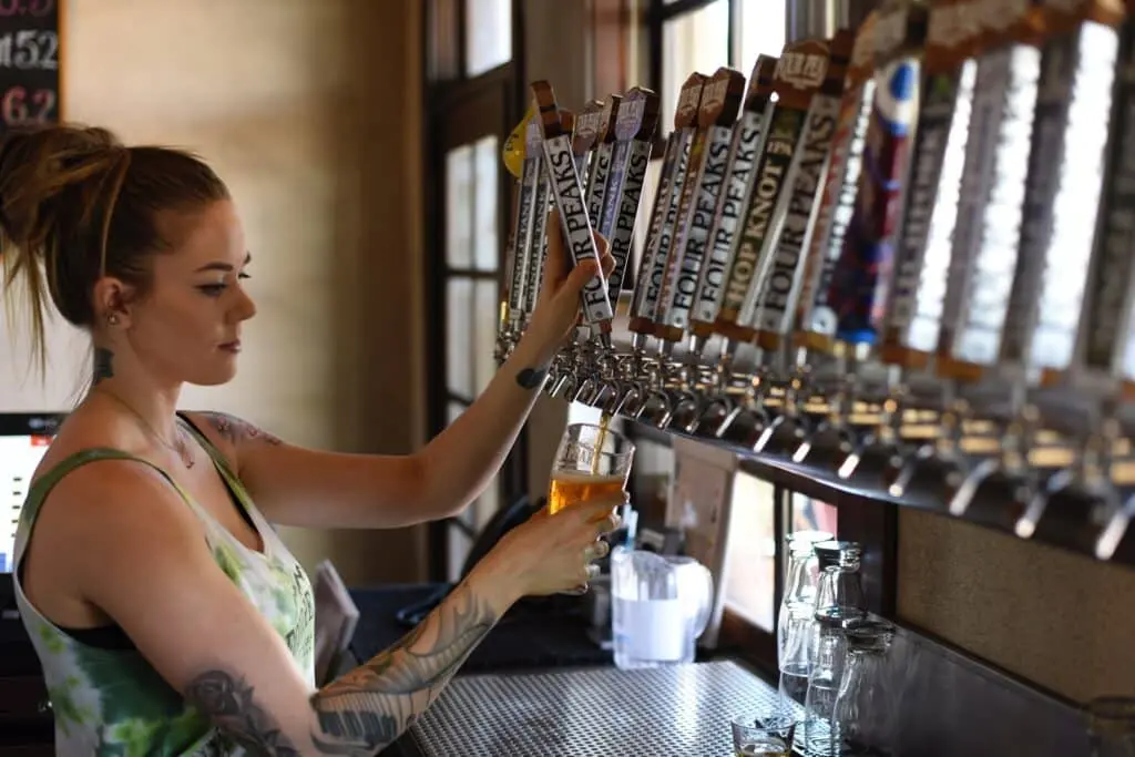 A woman pouring beer from the taps of a bar.