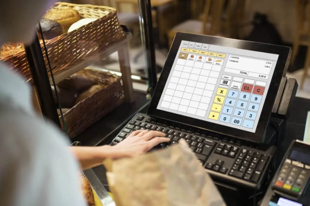 A person using a laptop at the counter of a bakery.