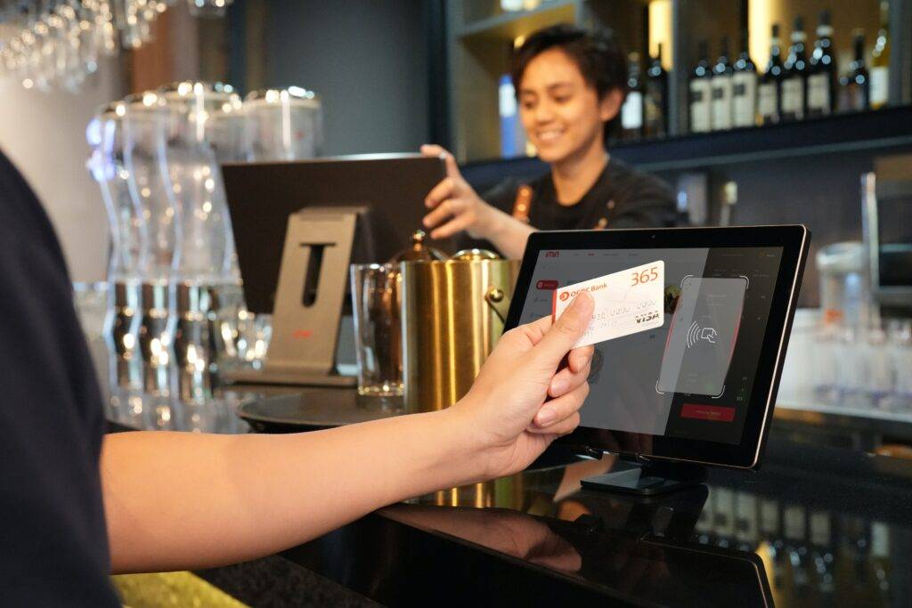A woman is paying for her purchase at the bar.
