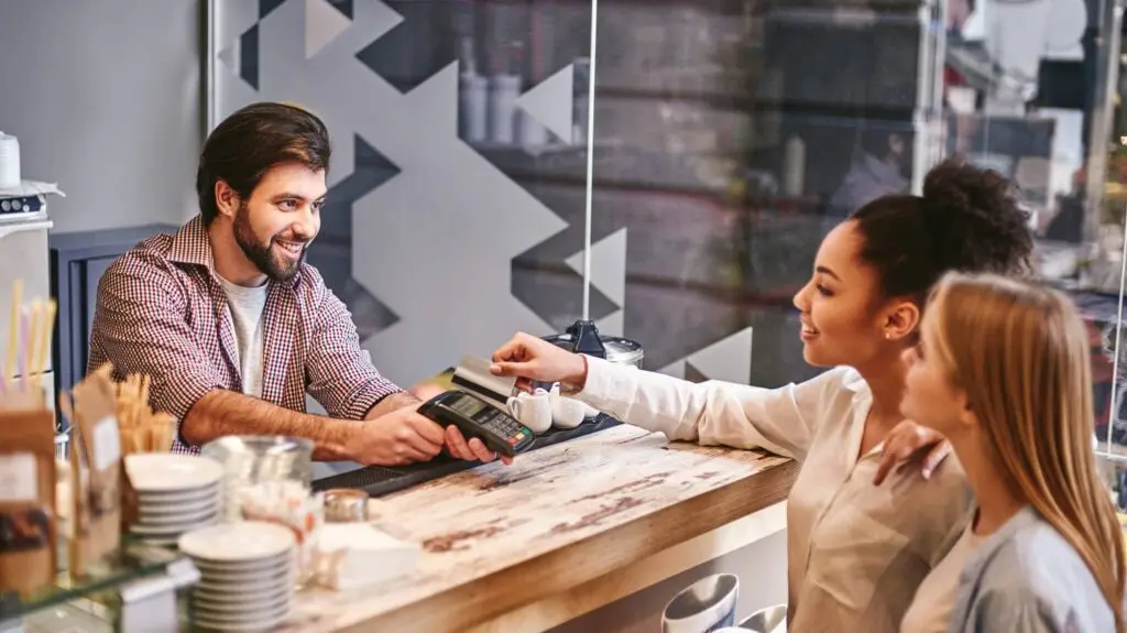 A man and woman paying for something at the counter.