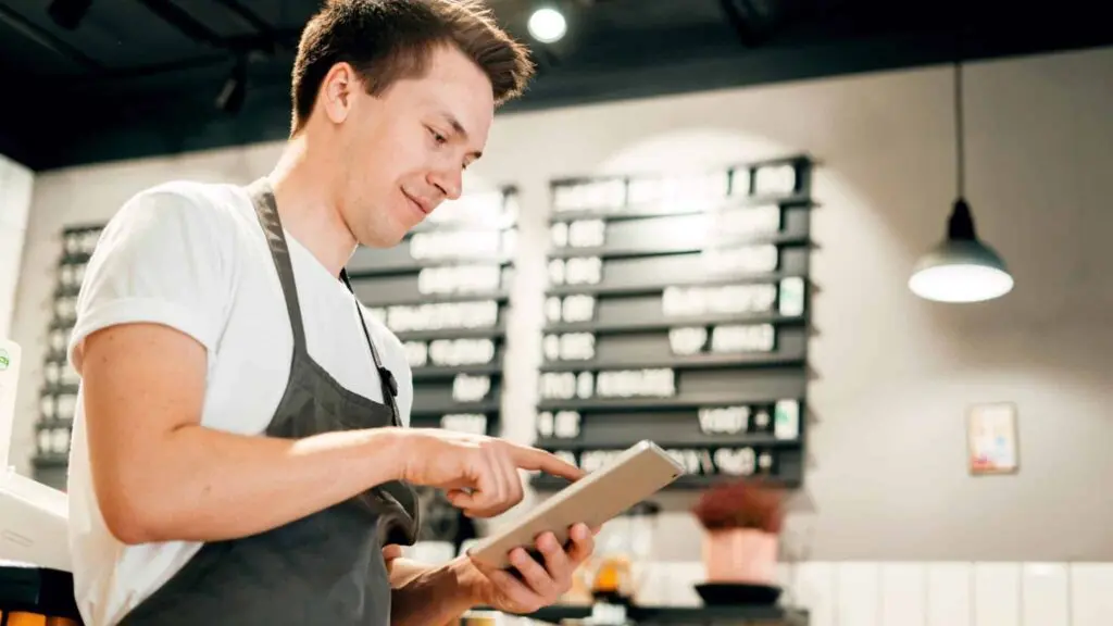 A man in an apron is using his tablet.