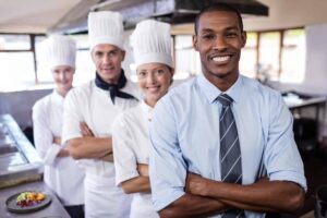 A group of chefs standing in line with their arms crossed.