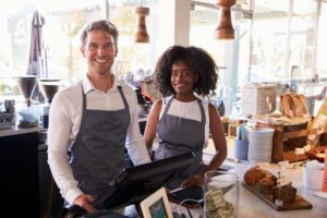 Two people in aprons standing at a counter.