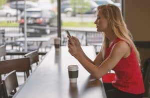 A woman sitting at a table with her phone.