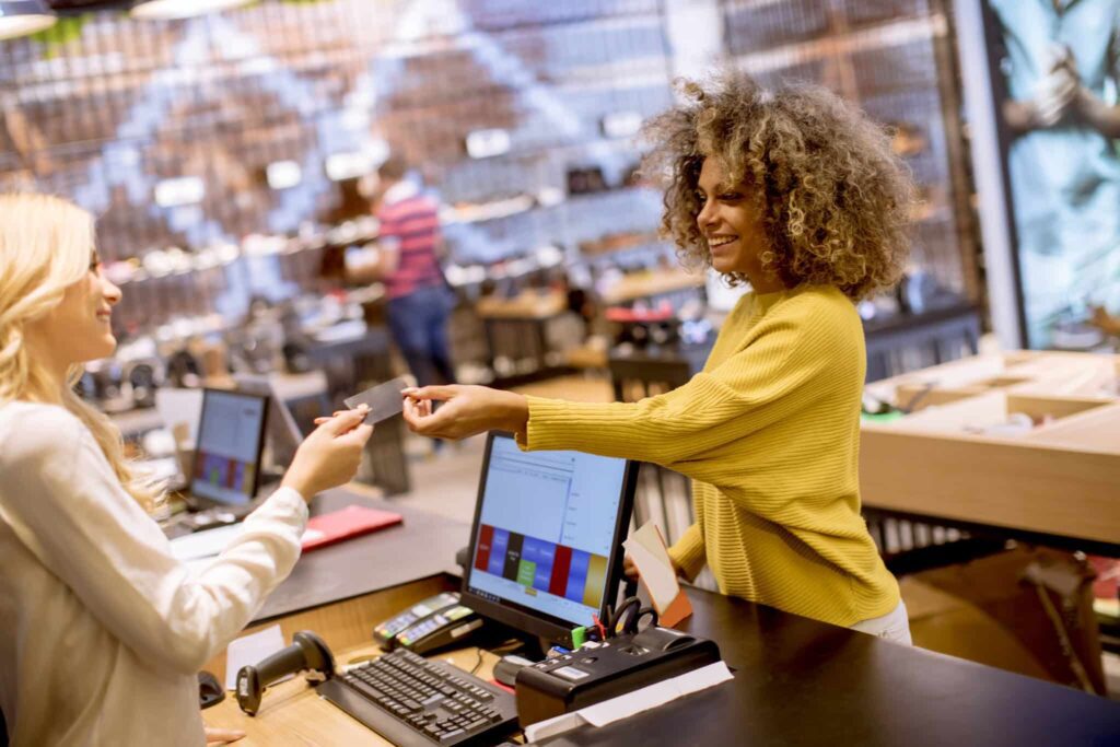 A woman is handing her credit card to someone else.