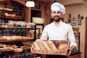 A man holding a basket of bread in a bakery.