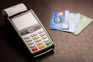 A credit card machine and some cards on the table.