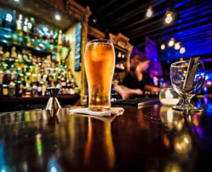 A glass of beer on the table in front of some people.