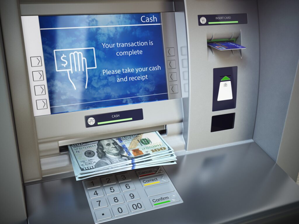 A cash machine with money on top of it.