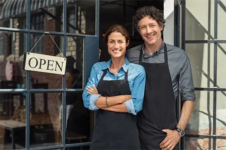 A man and woman standing in front of an open sign.