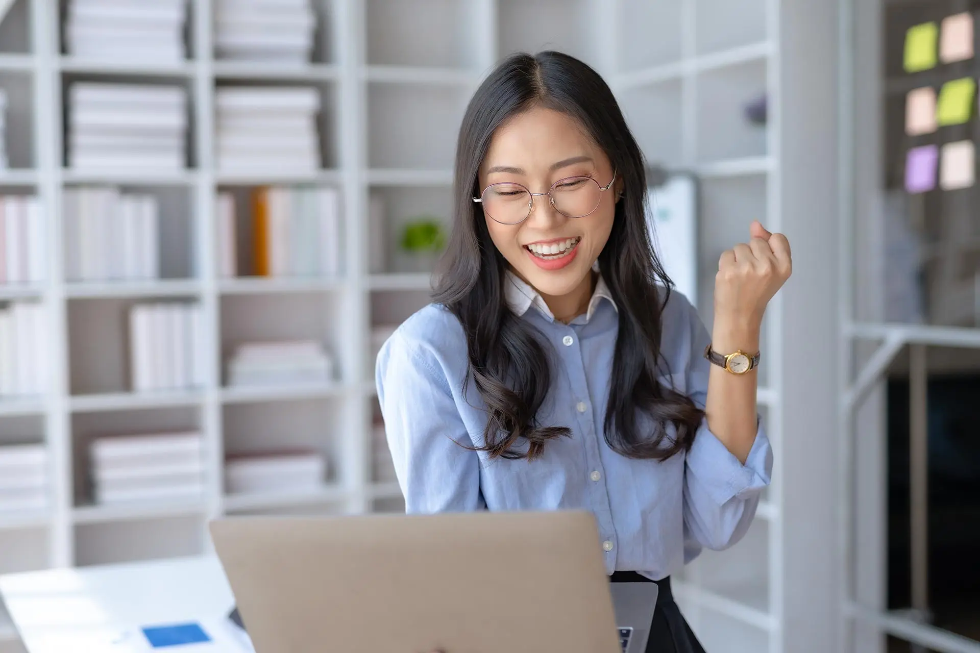 A woman is sitting at her desk with a laptop.