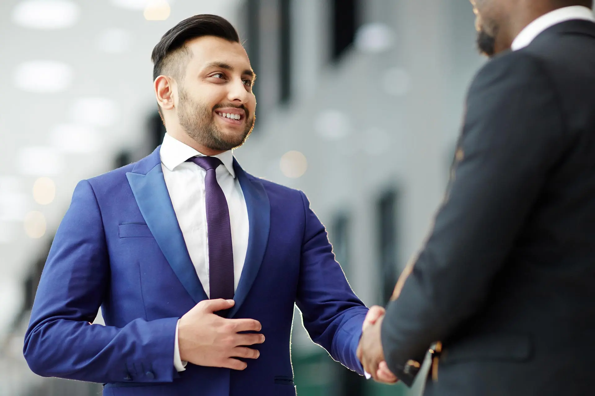 A man in a suit shaking hands with another person.