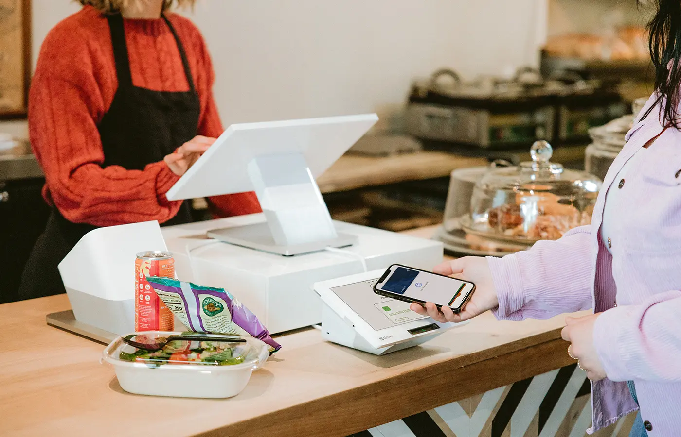 A person using their phone at the counter of a restaurant.